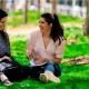 Mother and daughter sitting outside in the sunshine while talking and laughing